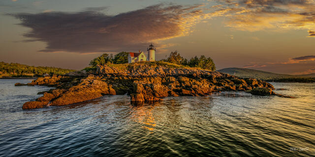 Curtis Island Lighthouse and keeper's house on a rocky island in Camden, Maine, lit by warm sunrise light over the headland