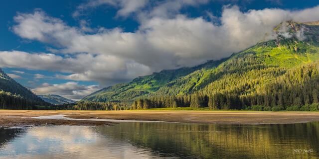 Scenic mountain valley with forested slopes, reflecting water, and cloud-filled sky on Admiralty Island Alaska