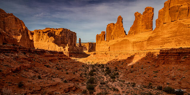 Towering sandstone fins rising above a desert canyon trail in Arches National Park, Utah
