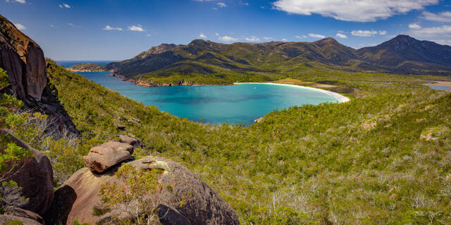 Turquoise Wineglass Bay surrounded by rugged mountains and native forest in Freycinet, Tasmania
