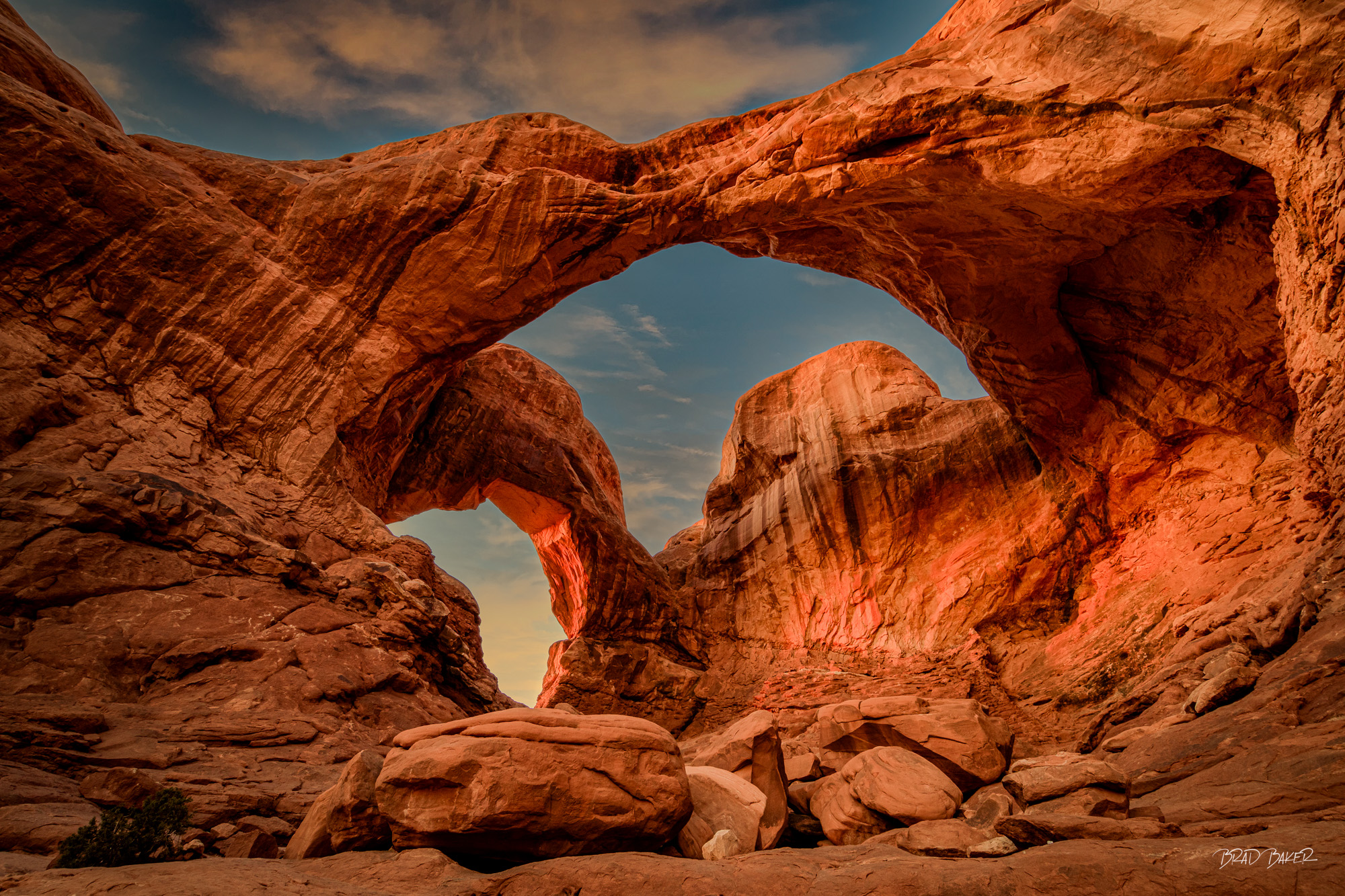 Canyon Serpent Red sandstone double arch glowing at sunset with desert sky in Arches National Park, Utah, USA