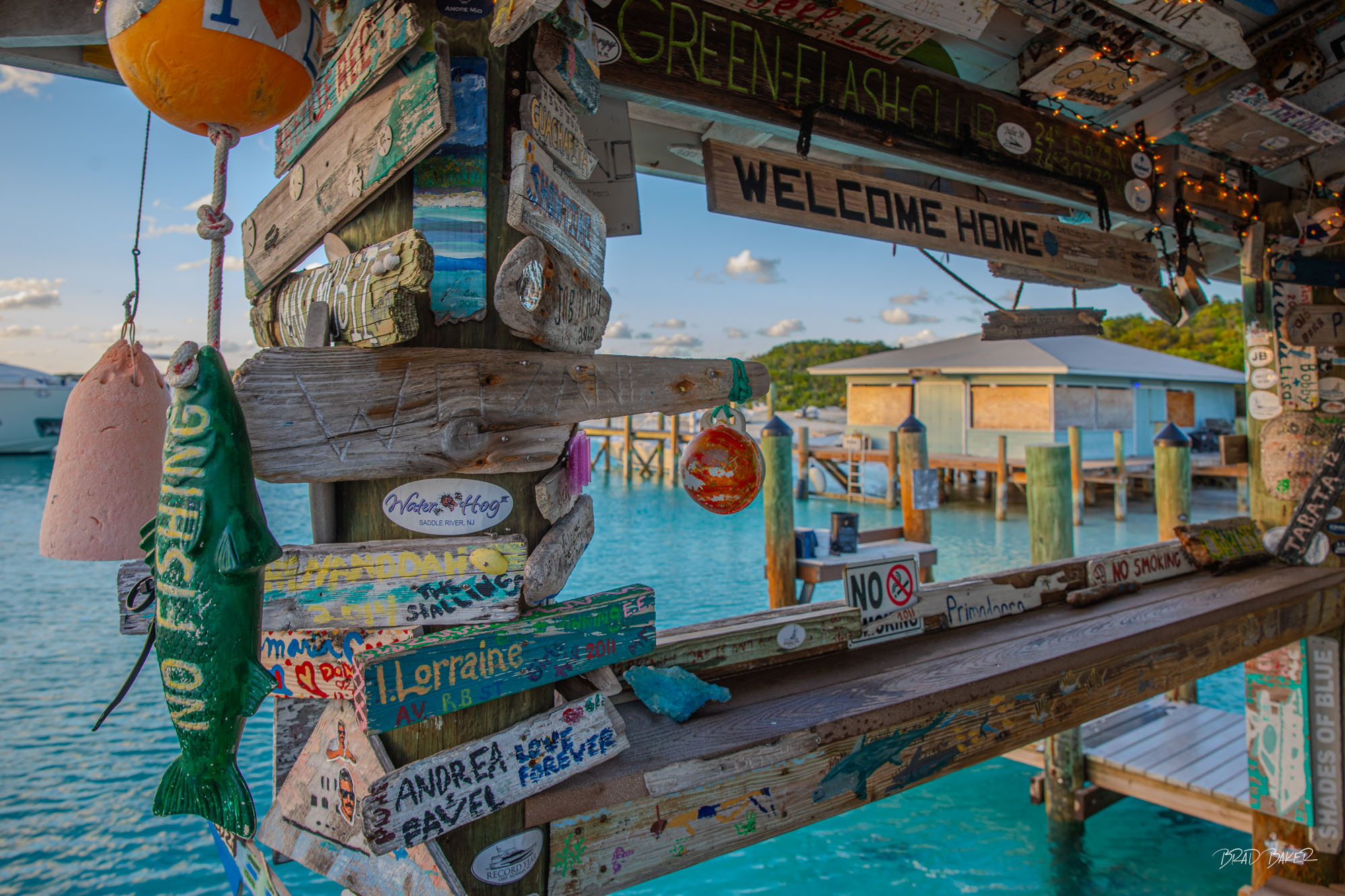 COMPASS CAY CLUTTER Colorful hand-painted signs and fishing decorations overlooking turquoise water at Compass Cay