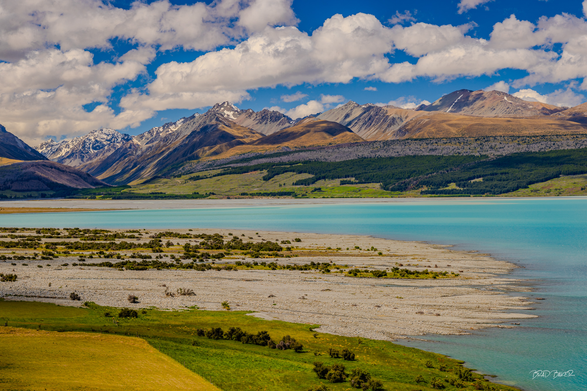 Layered Landscape Turquoise glacial Lake Tekapo with braided riverbed, green pastures and snow-dusted mountain ranges
