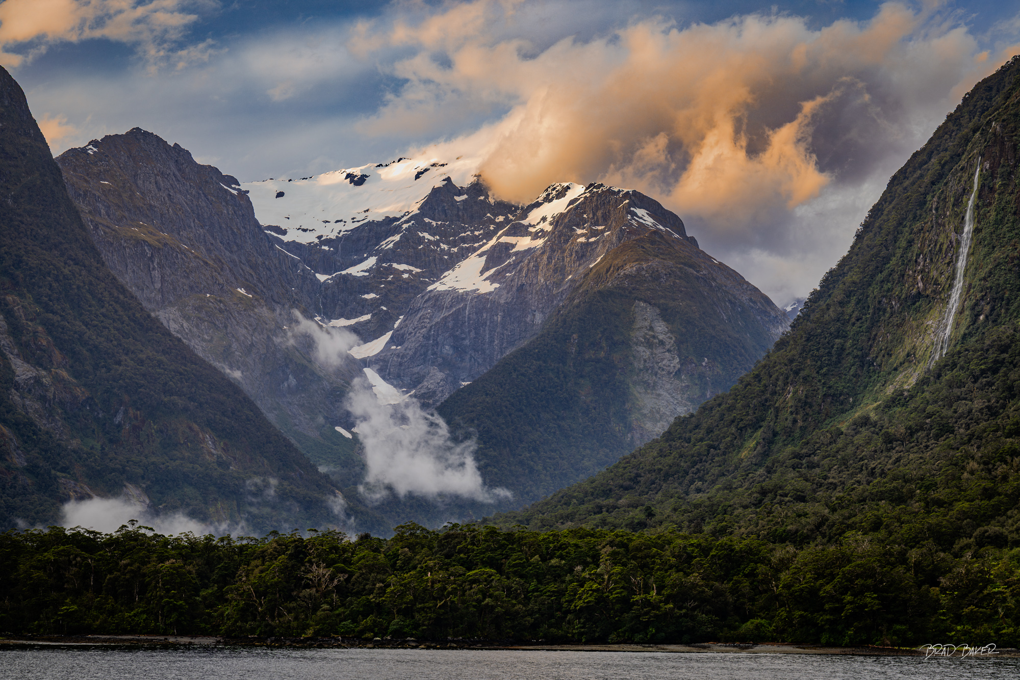The evening run off The rain clears, the clouds break, and the water continues to cascade down the distant peak and the foreground mountain slopes...