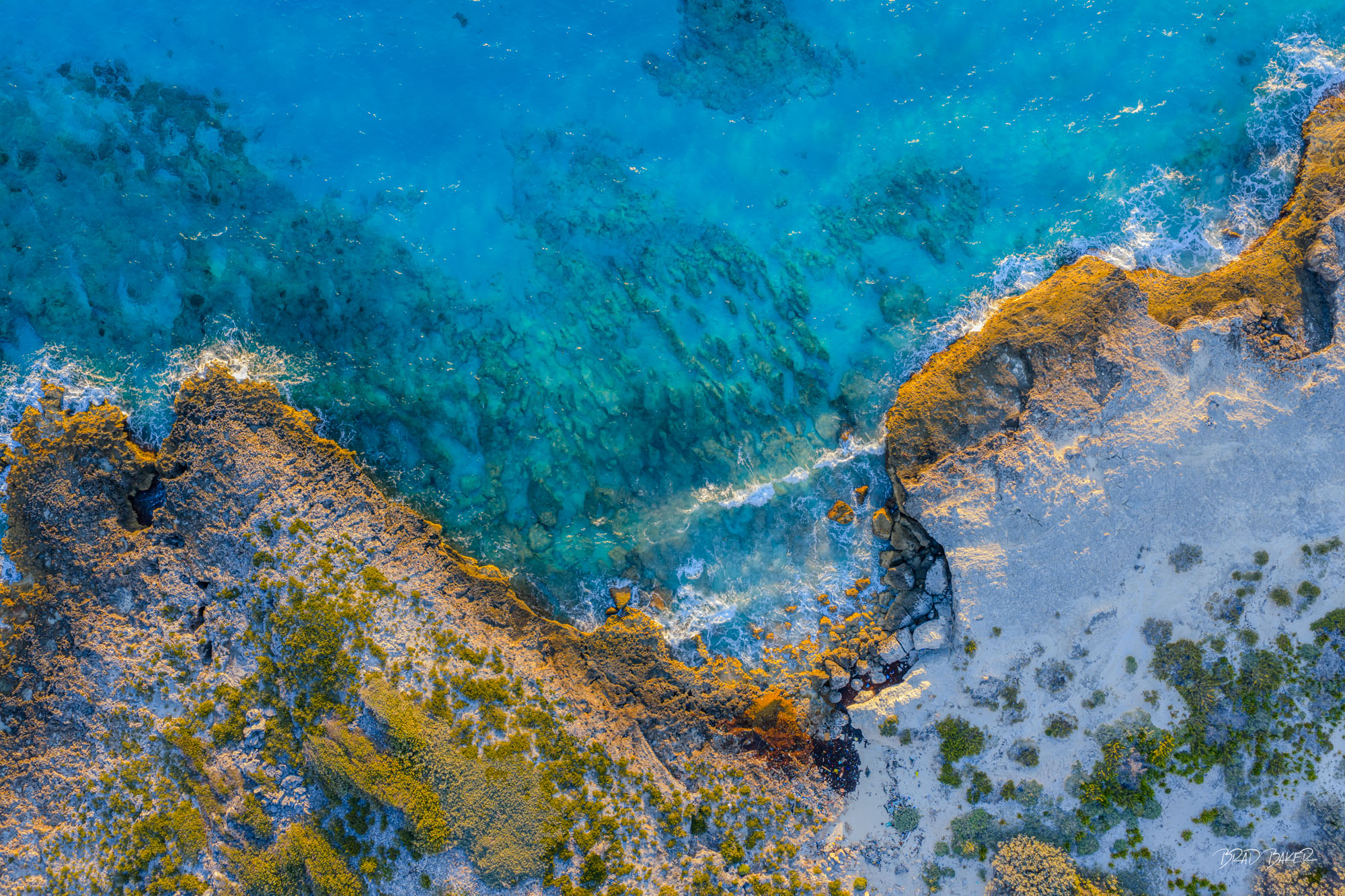 THE JAGGED EDGE Overhead view of jagged rocky coastline with turquoise water and scattered mangrove vegetation at waterline in The Bahamas