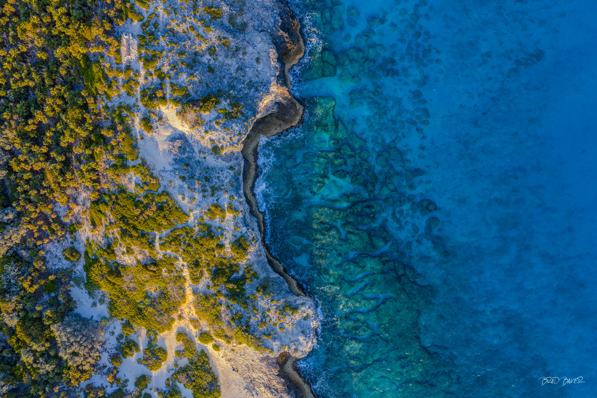 TWO WORLDS COLLIDE Aerial shot showing sharp contrast between shallow turquoise shallows and deep blue ocean near rocky coastline on Warderick Wells Exumas