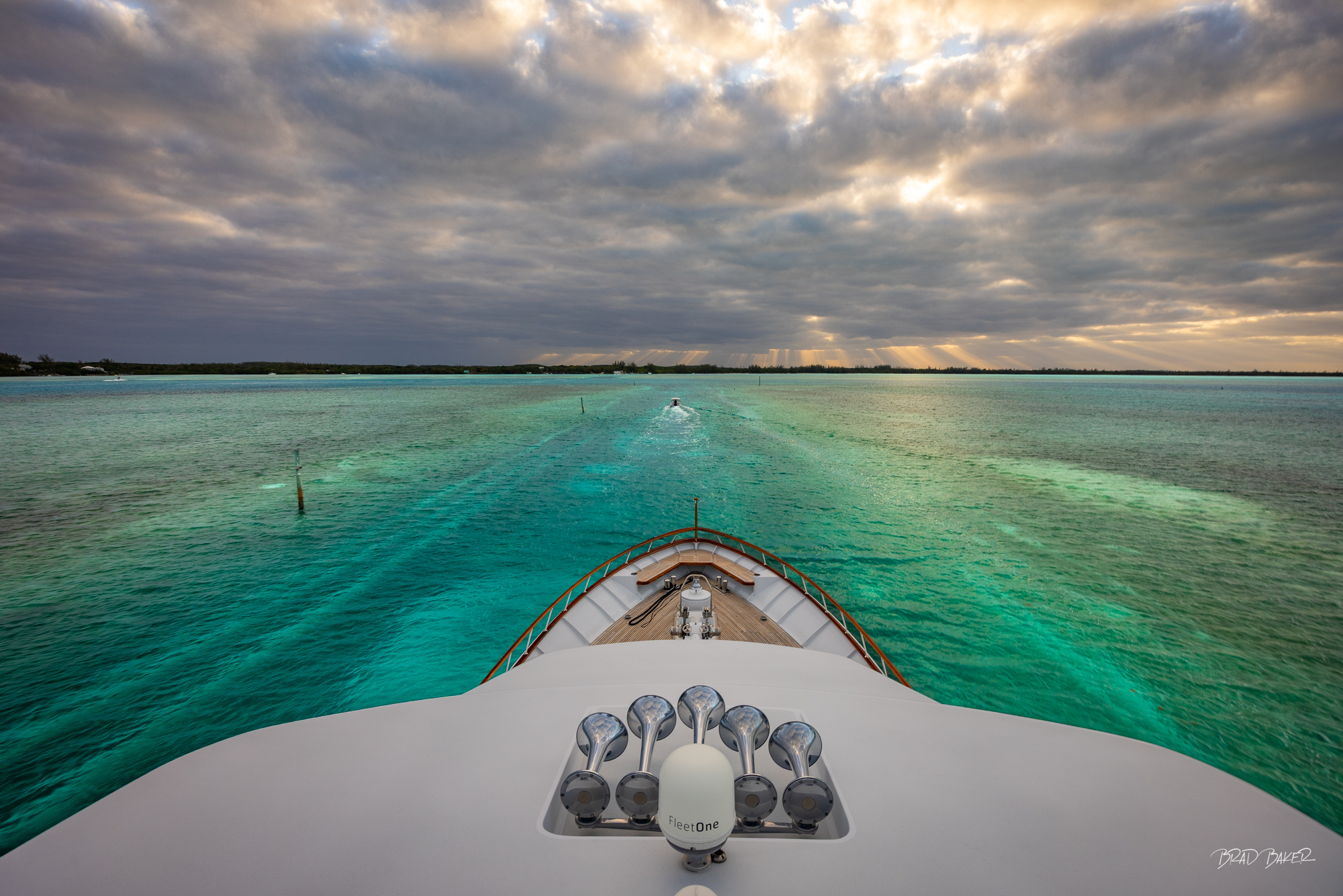 High Tide Only Yacht bow over turquoise Bahamian flats near Spanish Wells, with golden sunbeams breaking through the dark storm clouds